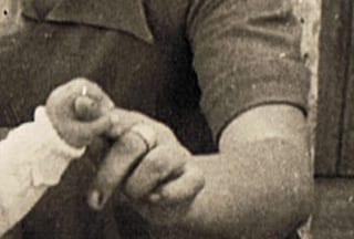 Cropped old photograph of an adult hand holding a toddler hand